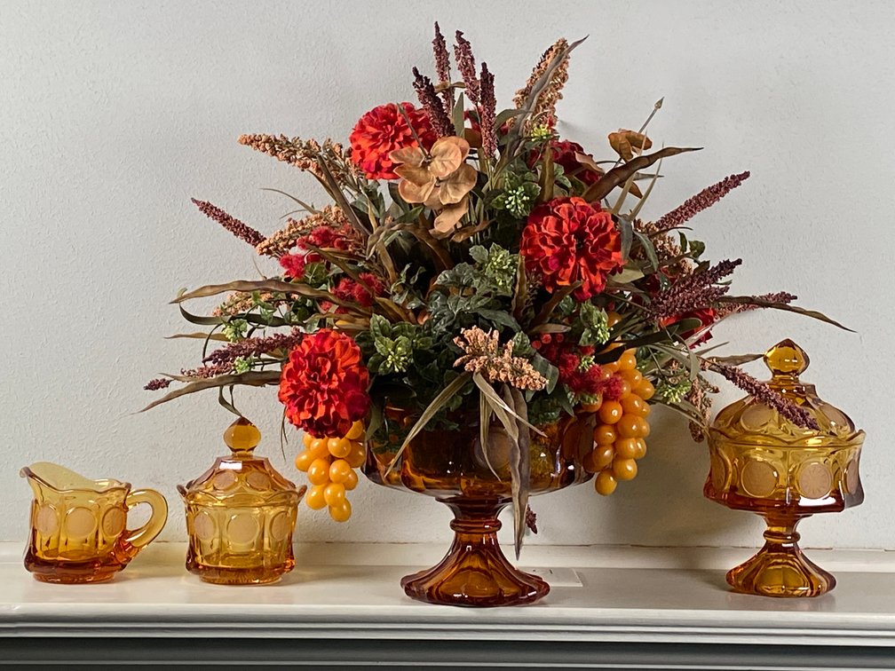 Collection of (4) Vintage Fostoria Amber Glass Coin Pattern Pieces Including Compote with Floral Arrangement, Footed Candy Dish with Lid, Candy Dish and Creamer