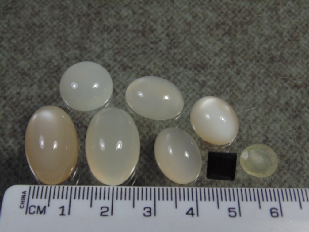 Six milky Moonstone cabs, 1 faceted Garnet and an unknown faceted stone, 16 grams