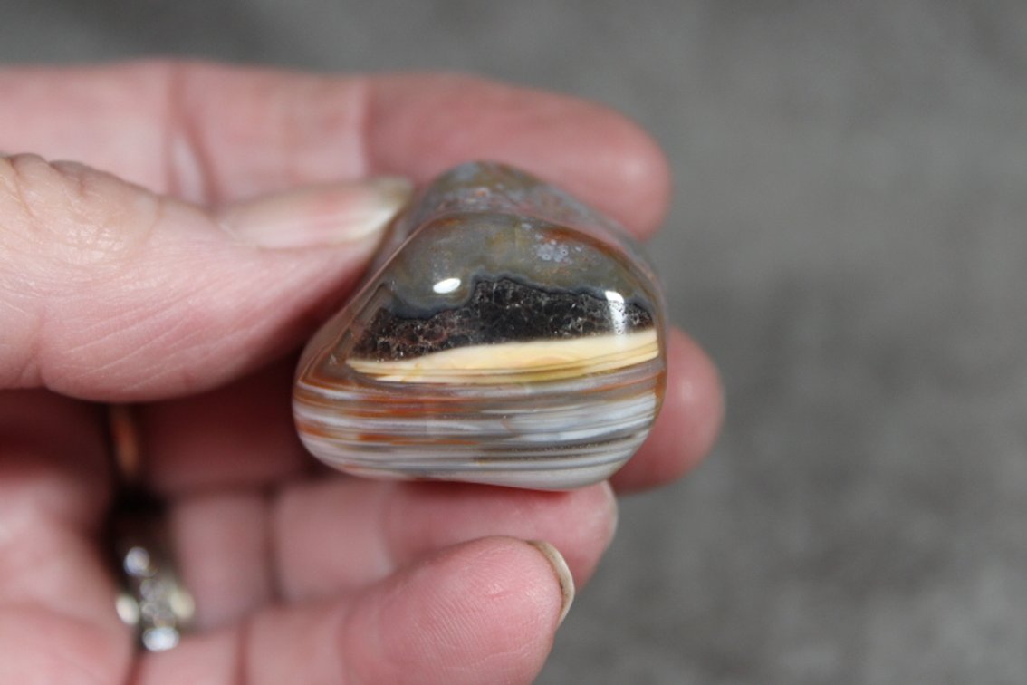 A .8 oz tumbled polished Lake Superior Agate with nice waterlevel banding and a pocket of Amethyst