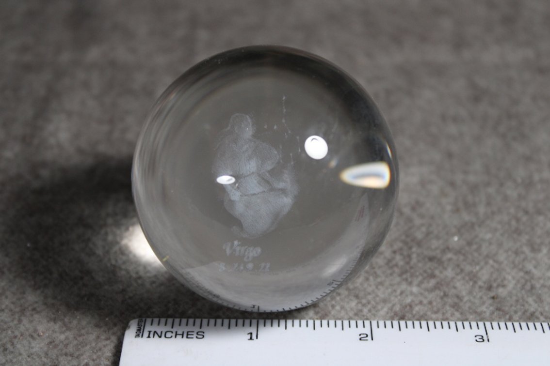 A glass sphere with the lasered image of the Zodiac sign Virgo, sphere shown on light box which is not included
