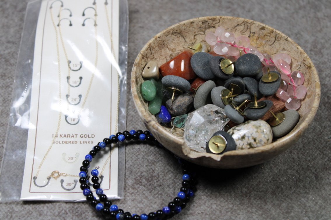 An assortment of stones, in a fossil bowl, a 14K gold chain and a beaded bracelet