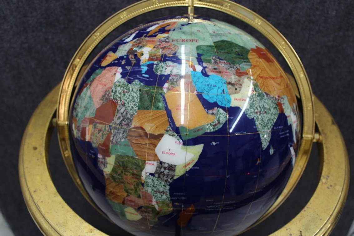 A floor standing Lapis globe with countries highlighted by different stone inlay, the brass stand shows lots of wear