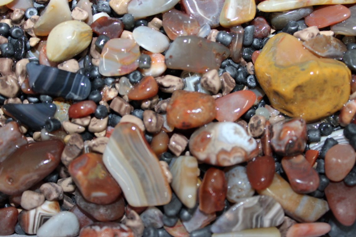 A 9 lb 8 oz flat of Lake Superior Agates and tumbling media. The agates have gone through the first stage of tumbling giving them a satin finish. They can either be left as is or put back in the tumbler for a higher polish