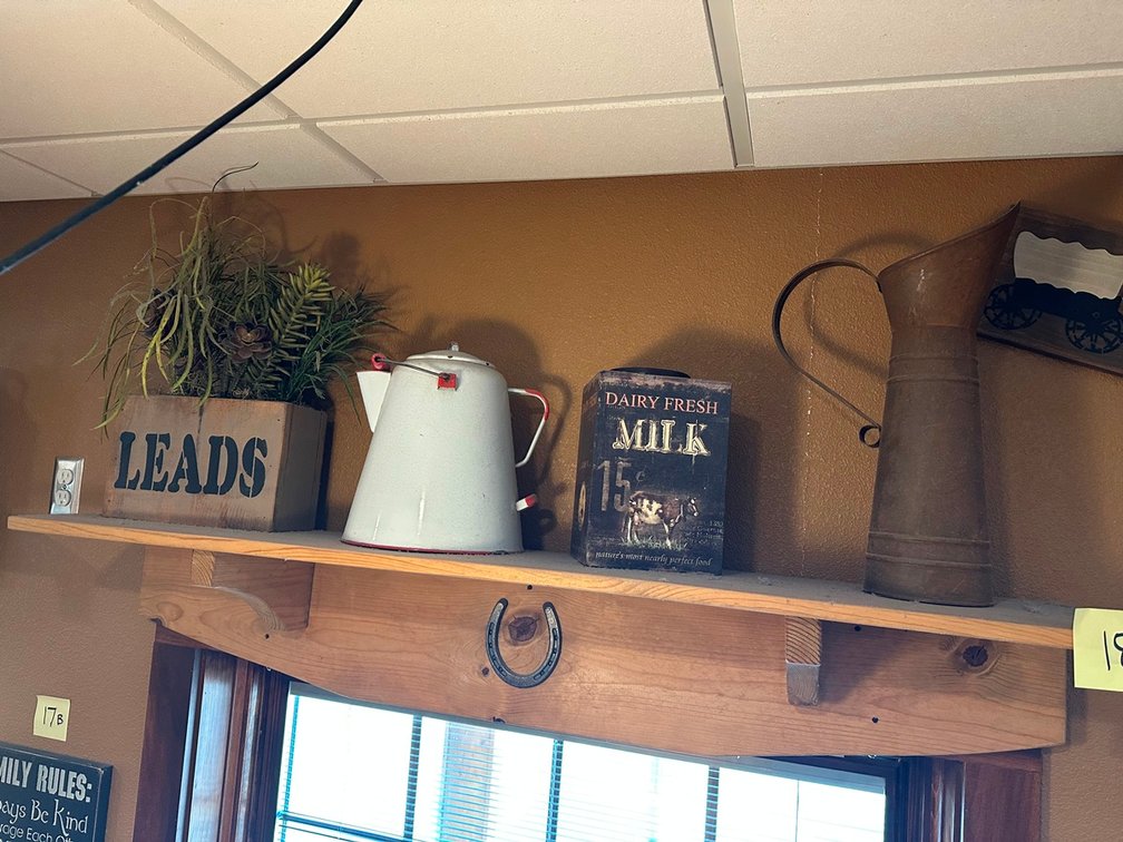 Shelf + plant + coffee pot + milk + pitcher + Prairie Schooner sign