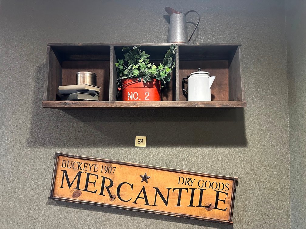 Mercantile sign & big wood shadow box + books + small tin + plant + white coffee pot + tin pitcher