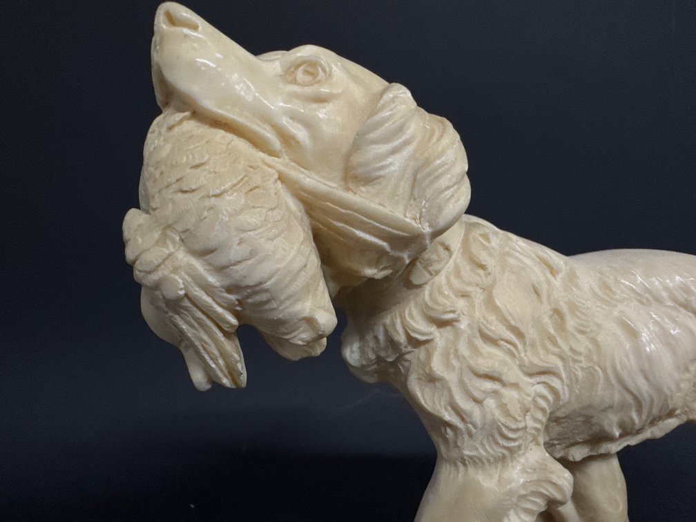 Molded composite statue of bird dog carrying its trophy