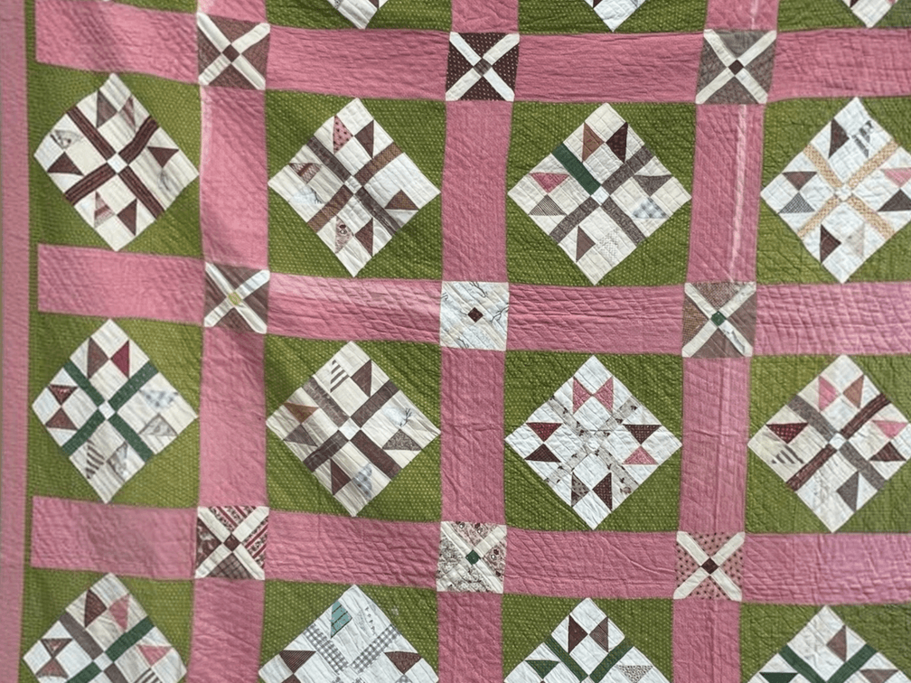 Vintage hand stitched quilt in Crossroads or Churn Dash block pattern in pink, green and brown