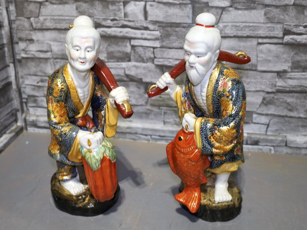 Large porcelain statues of Chinese man and woman with fishing gear and oriental pocketbooks