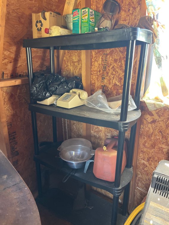 Black plastic shelving unit with miscellaneous contents
