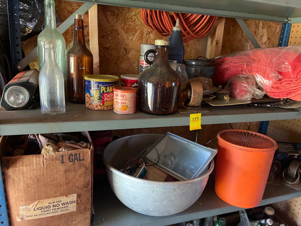 Two shelf lot of miscellaneous items including bottle jack, pack of hand rags, vintage bottles, & more
