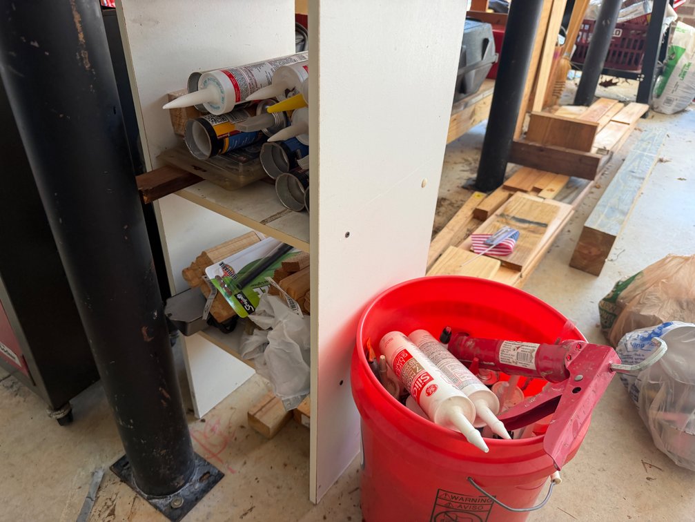 Caulking Gun, Sealant Cartridges, Wooden Stakes, and Shelving Unit
