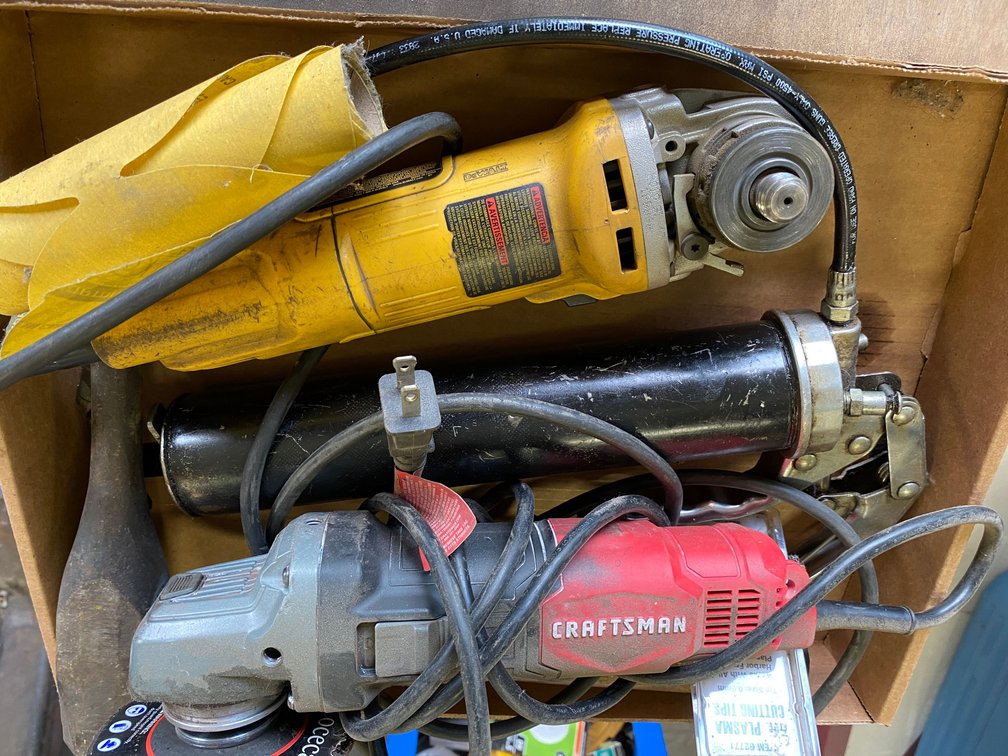 2 Fuel cans, a full can of motor mix for a trimmer, metal stand and some power tools, angle grinder and grease gun