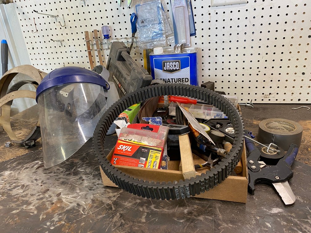 Flat of misc. items, face shields and contents on the pegboard right above:  1942 License plate and some straight wrenches