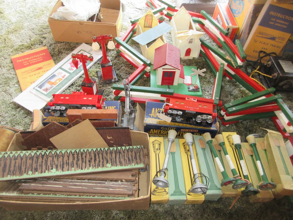 Large assortment of Lionel train pieces:  Cars, boxes of track, displays, several transformers and some boxes of Lionel train parts and track that are not in the picture