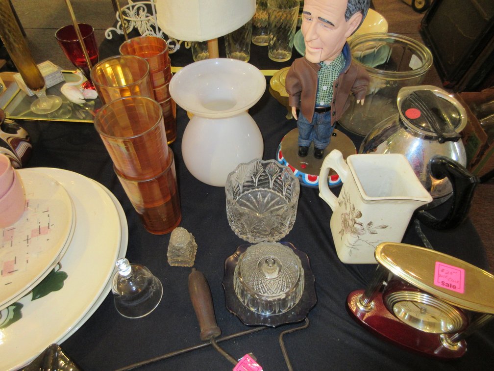 Table full of assorted glasses, some plates, clock, small Indian dolls, some milk bottles, vases, small cream and sugar, Sun Bonnet Babies plate
