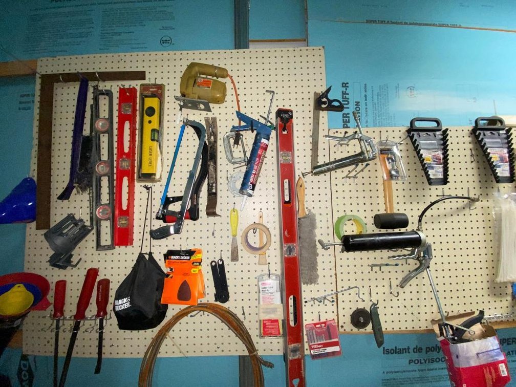Contents of wall pegboard:  Levels, hacksaw, jigsaw, squares, grease gun, wire brush, other items