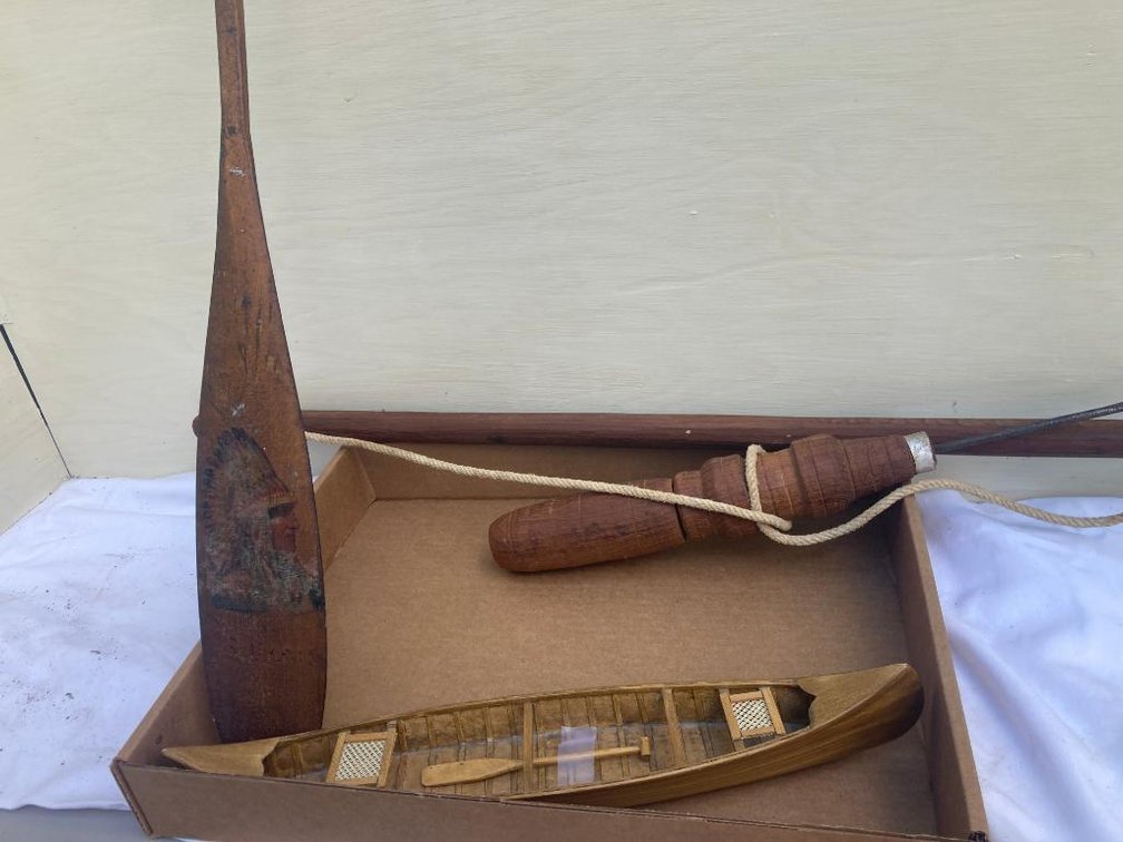 Model canoe, replica of antique Kuwaiti drill, and decorative Indian-themed wooden canoe paddle