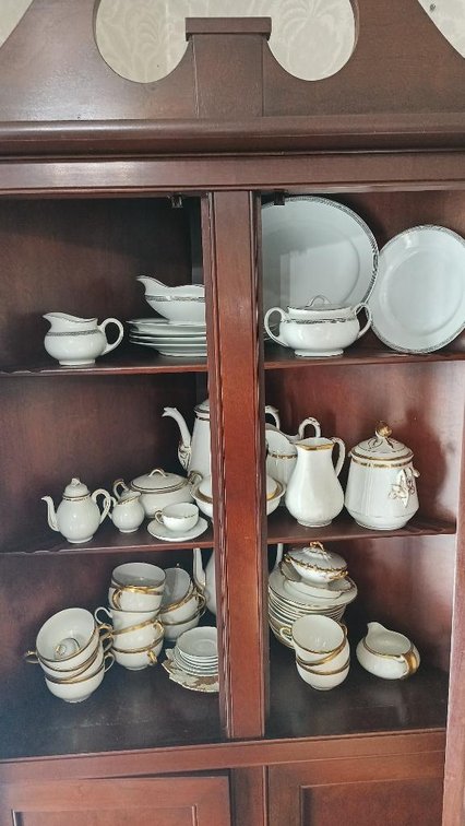 White dishes with gold trim in cabinet upper shelves