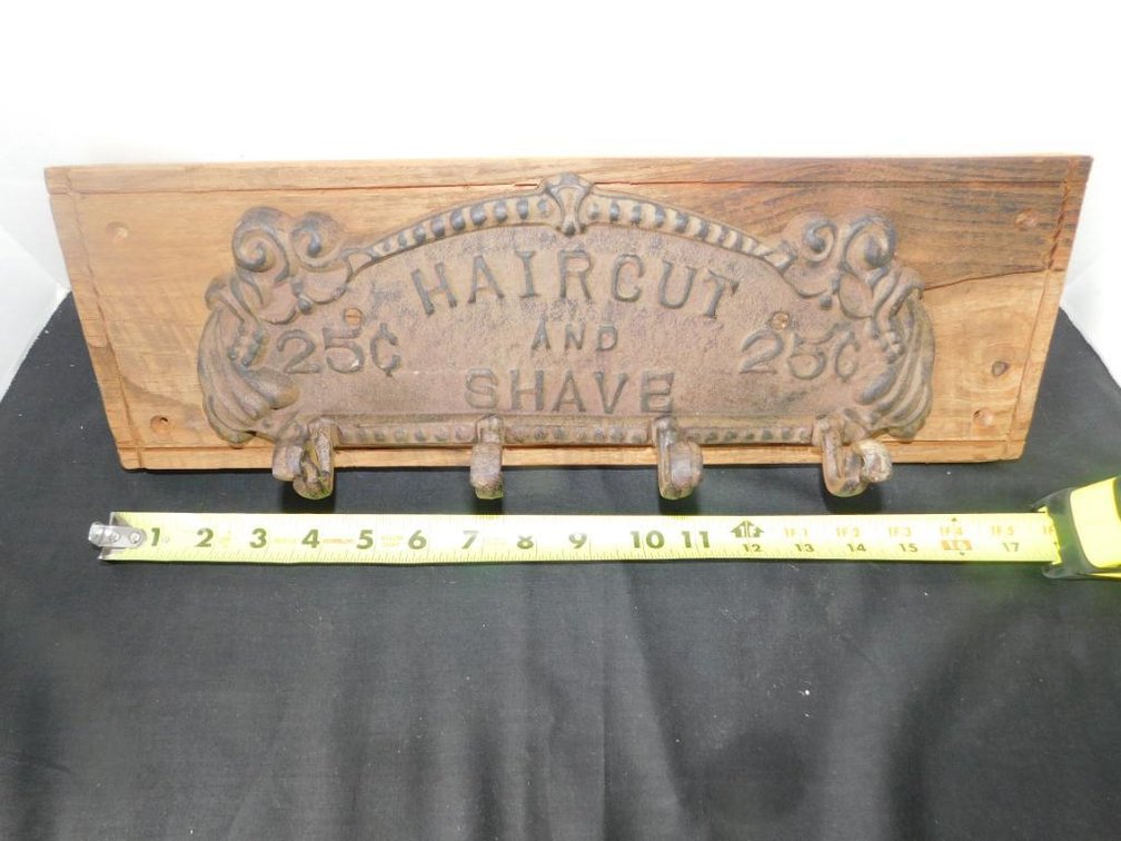 Cast metal haircut and shave coat rack mounted on board