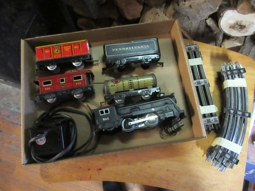 Marx Triple 6 engine, Santa Fe oil tanker #553, Pennsylvania Tender, Northern Pacific coal car #554, New York Central caboose 556, pieces of track & a transformer
