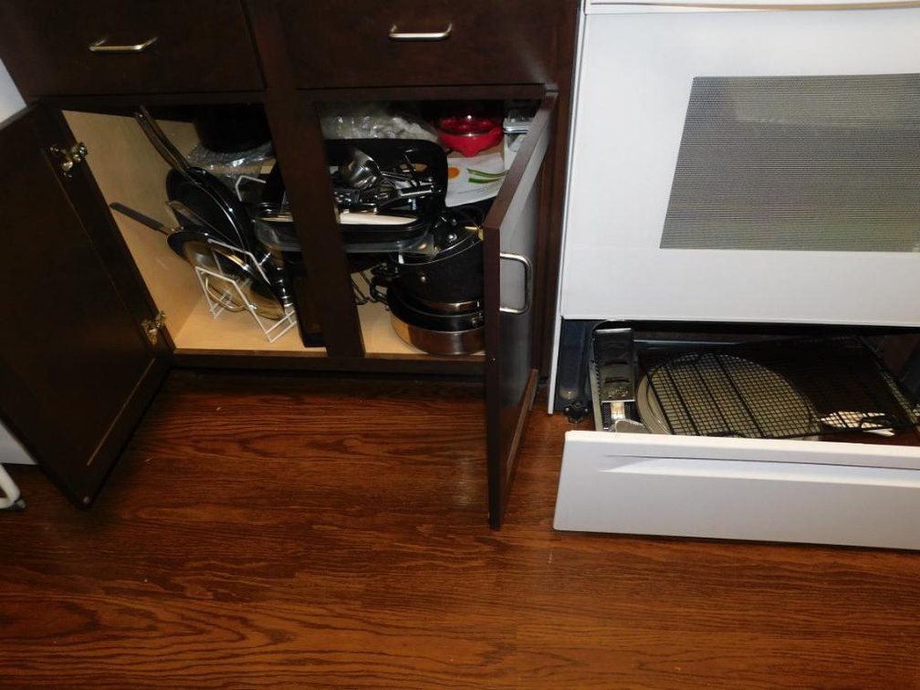 Lower cabinet to include serving pieces, skillets, pans, ?, cast iron covered Dutch oven & 3 cast iron skillets