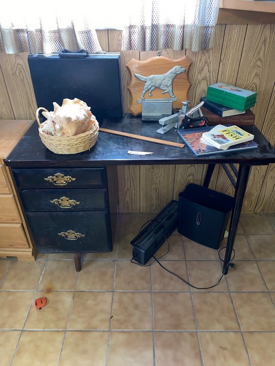 Desk w/ staplers, seashells, TV, books
