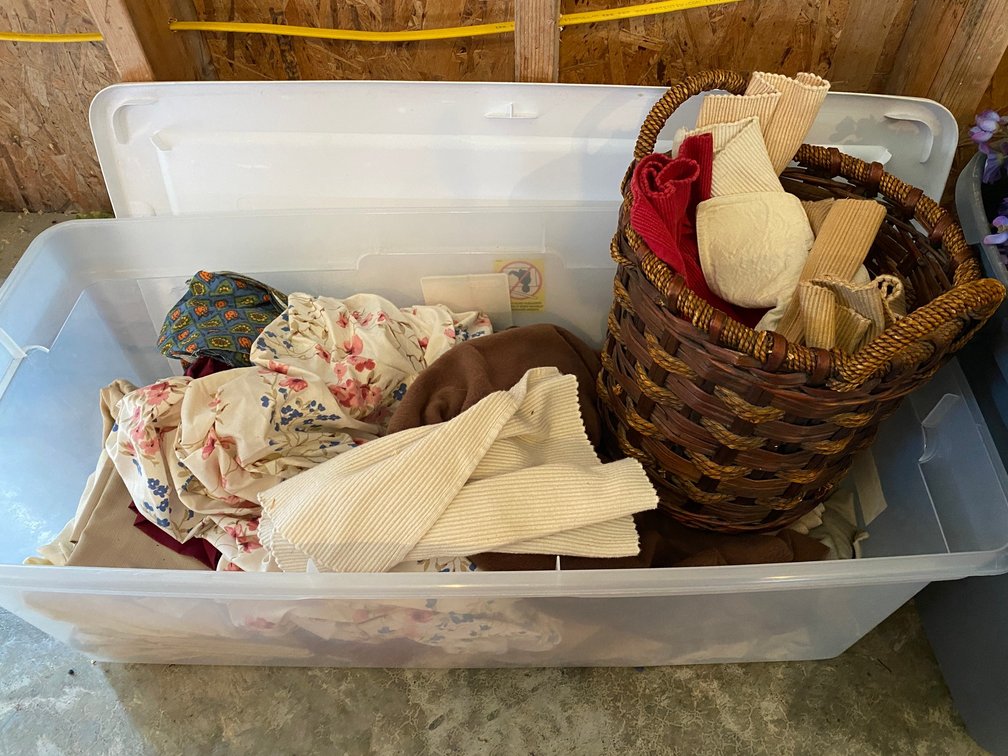 Tote with lid filled with variety of linens and nice wicker basket