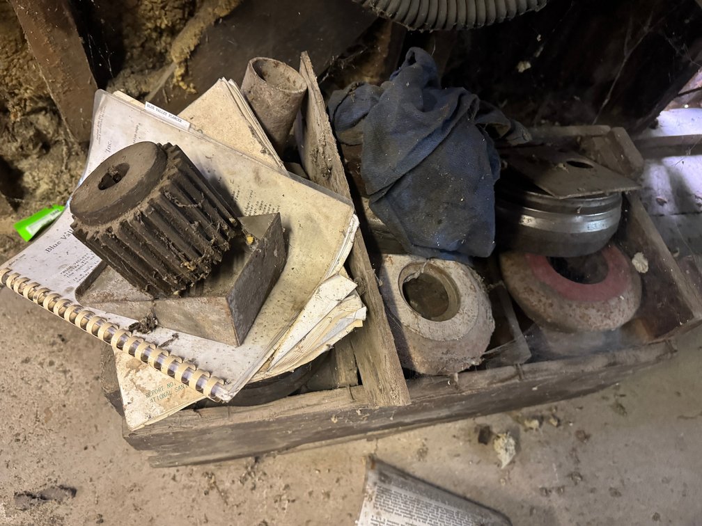Assorted grinding wheels, abrasive discs, and small industrial/shop components stored in a wooden crate.