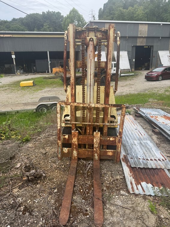 Older industrial forklift with extended mast and forks.