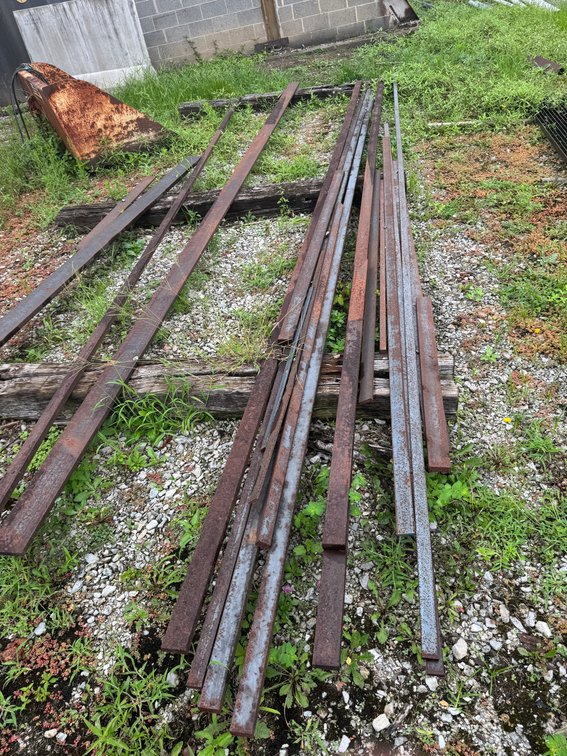 Assorted steel angle iron, flat bar, and metal stock in various lengths.