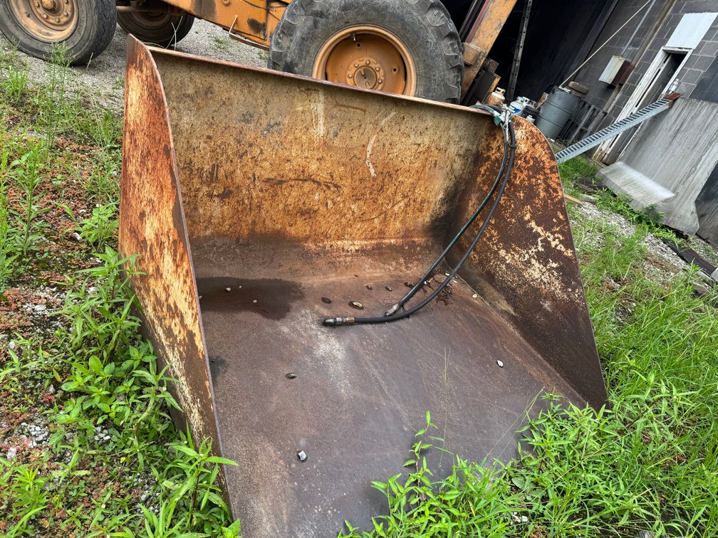 Heavy-duty loader bucket attachment with hydraulic lines.