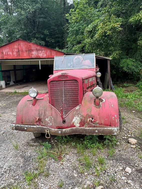 Vintage Economy Tank fire truck with open cab, hose reel, ladder, and rear equipment body.