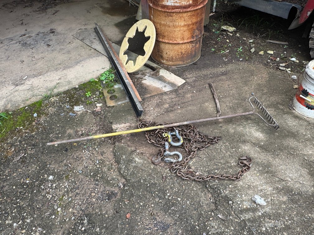 Assorted heavy-duty chains, hooks, and shackles for lifting, towing, or rigging applications and rake.