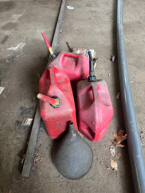 Assorted fuel cans with spouts and a large funnel.