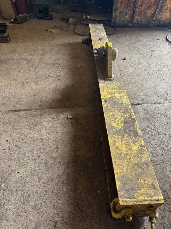 Heavy-duty yellow lifting/spreader beam with lifting eye and end hardware.