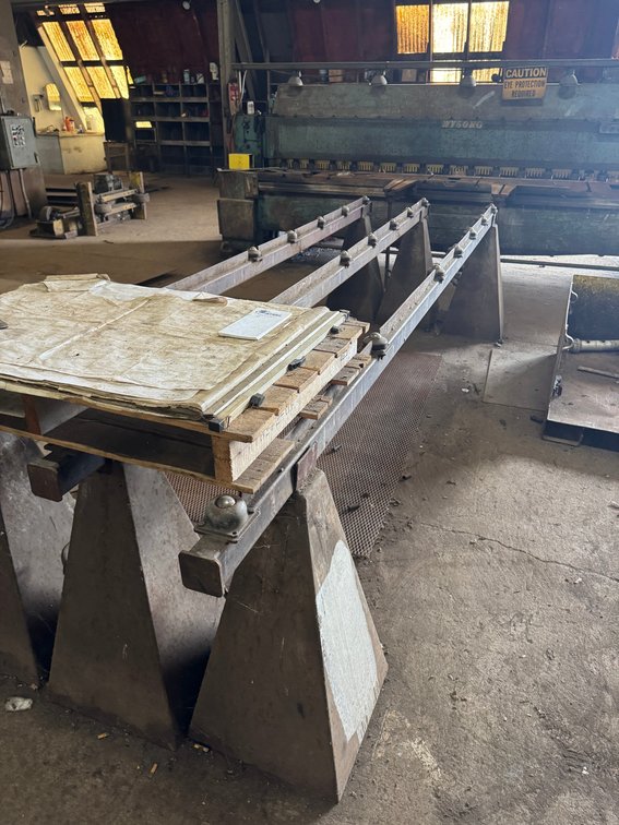 Heavy-duty industrial sheet metal support arms and material table.