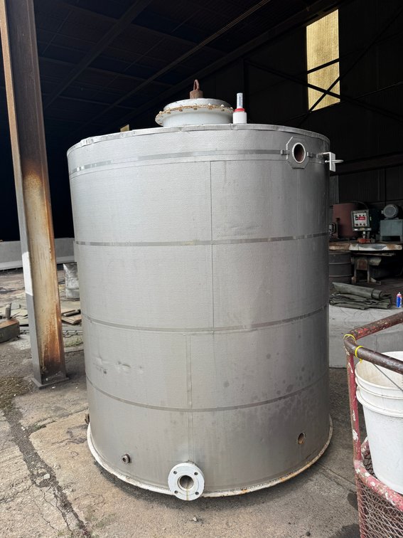 Large vertical stainless steel storage/process tank with top access hatch and multiple side/bottom ports.