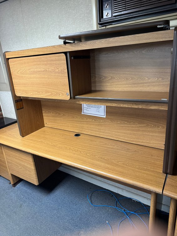 Wood-grain office desk/workstation with overhead hutch, storage cabinet, shelving, and built-in drawers.