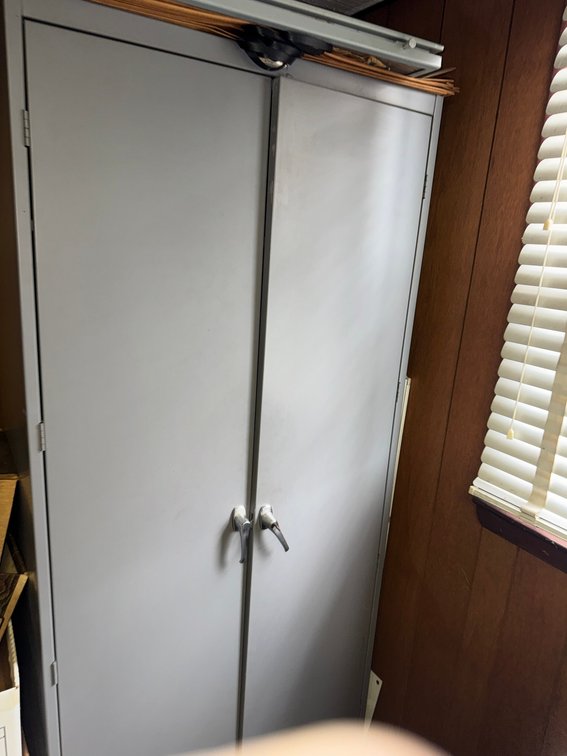 Tall gray metal storage cabinet with double doors and locking handles.