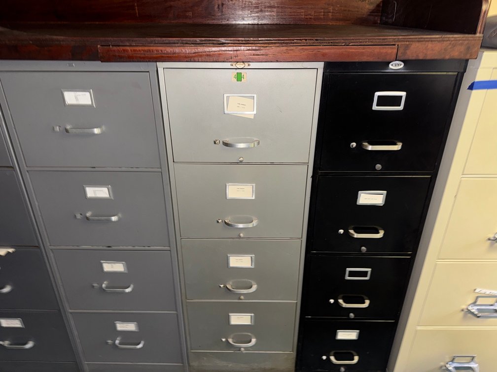 3 metal filing cabinets in multiple colors and sizes with label holders and drawer handles.