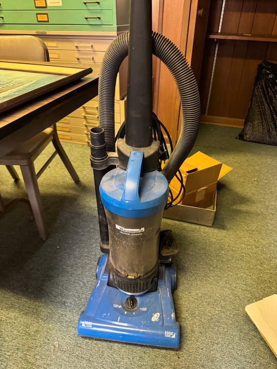 Commercial upright vacuum cleaner with hose attachment and bagless dirt canister.