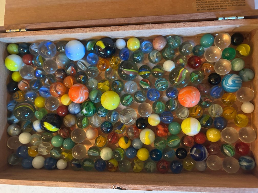 Collection of mixed marbles in a Padron cigar box