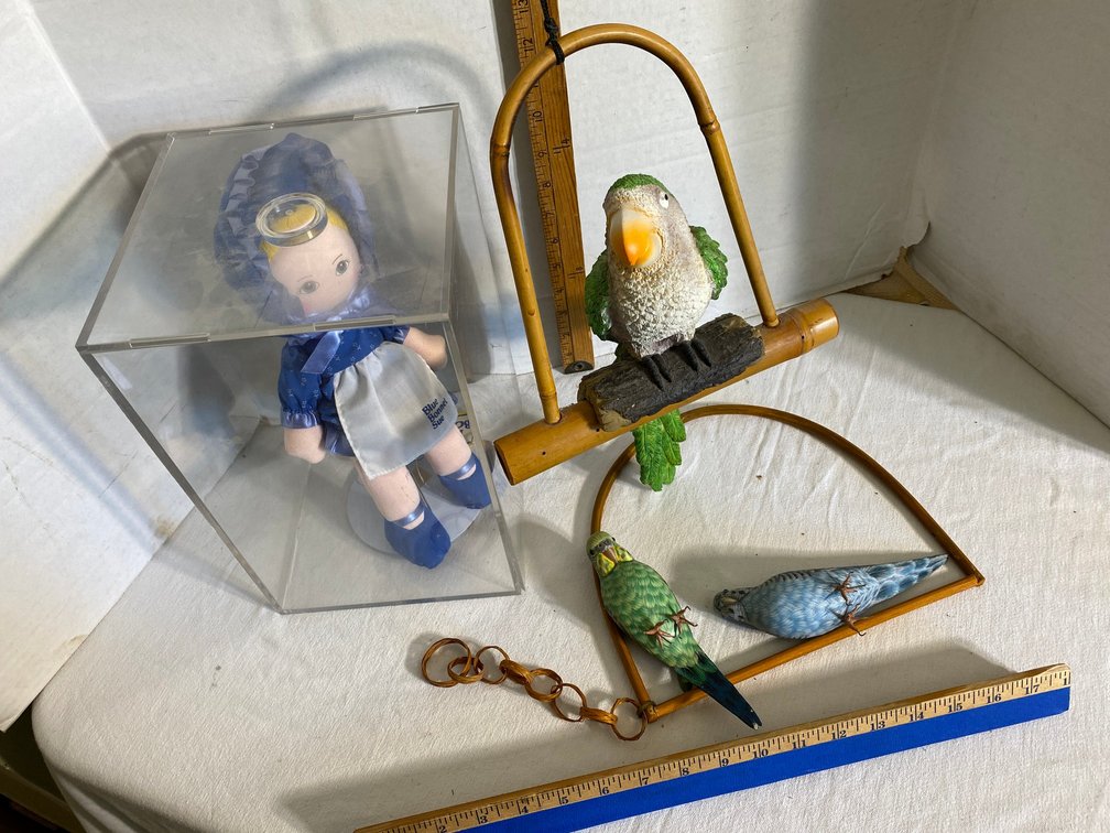 Blue Bonnett Sue doll in a display case, decorator parrots on swings