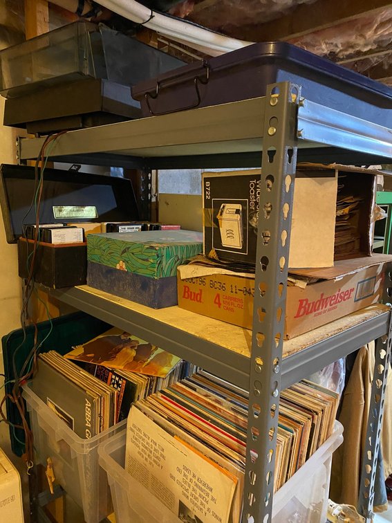 Metal frame shelf with pressed wood shelving, many vinyl records, some 8-track tapes, some 45 records, record cabinet, record player