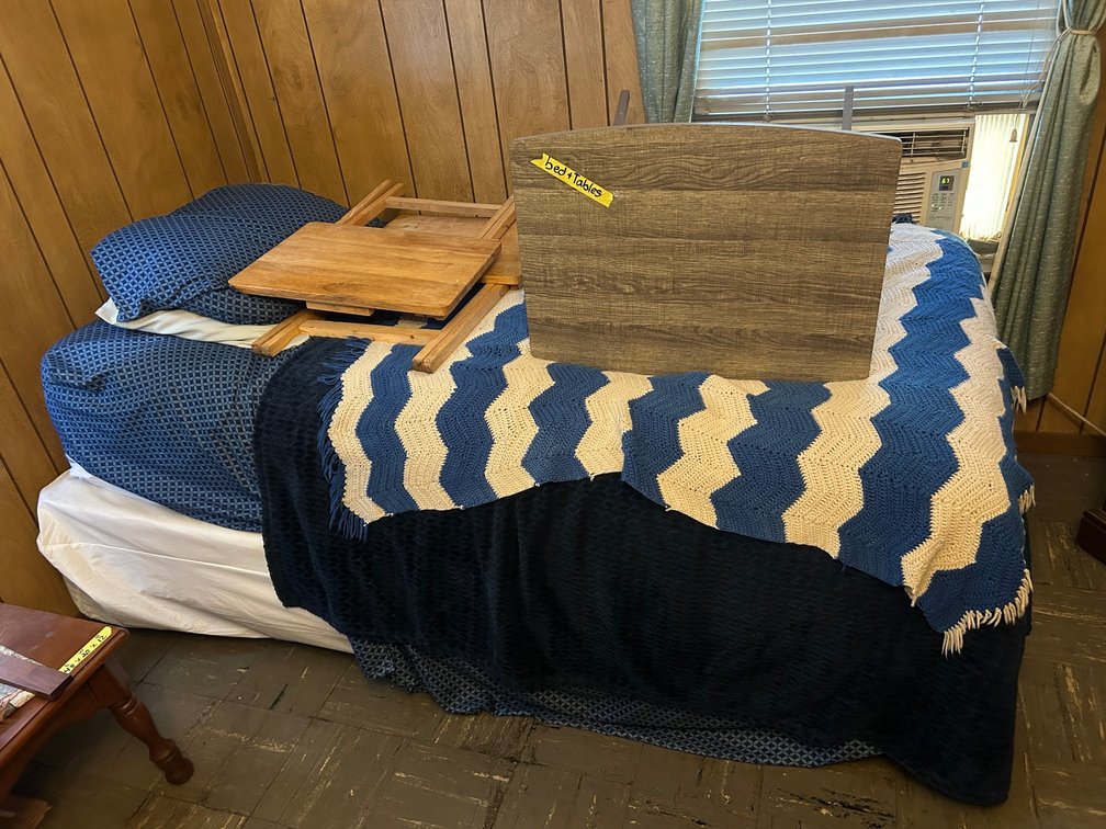 Twin size bed with blankets, folding tables