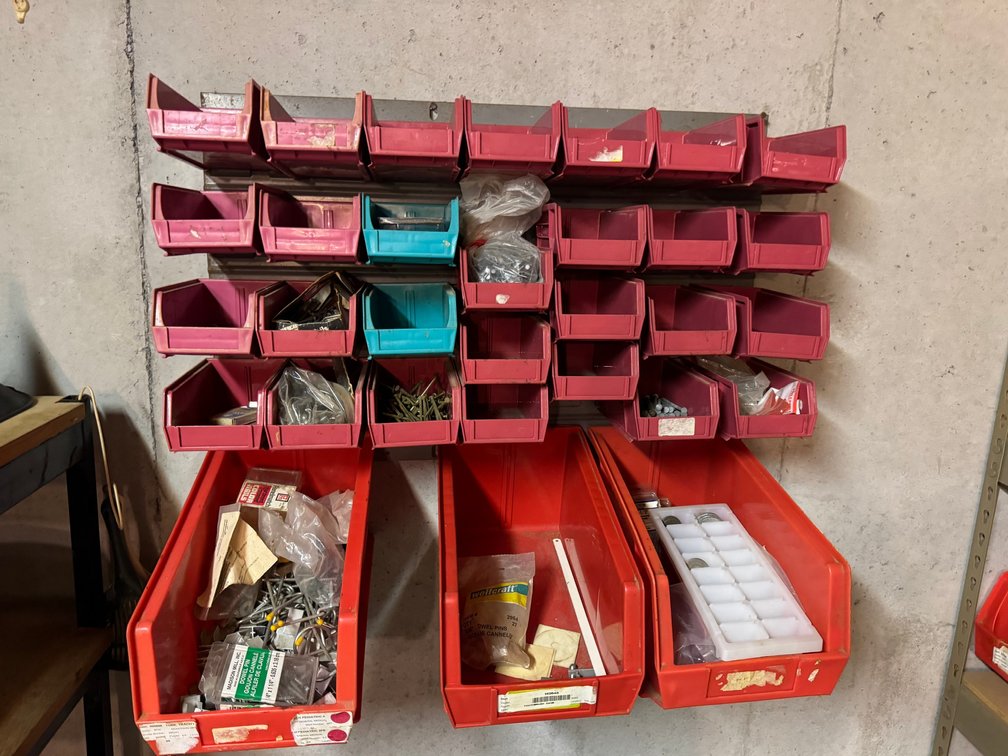 Red plastic stacking hanging bins filled with screws, nuts and bolts