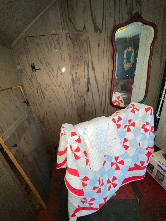 Wall mirror, red full size quilt, blue crib quilt