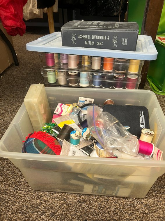Sewing box with numerous spools of thread, pins, and other sewing accessories
