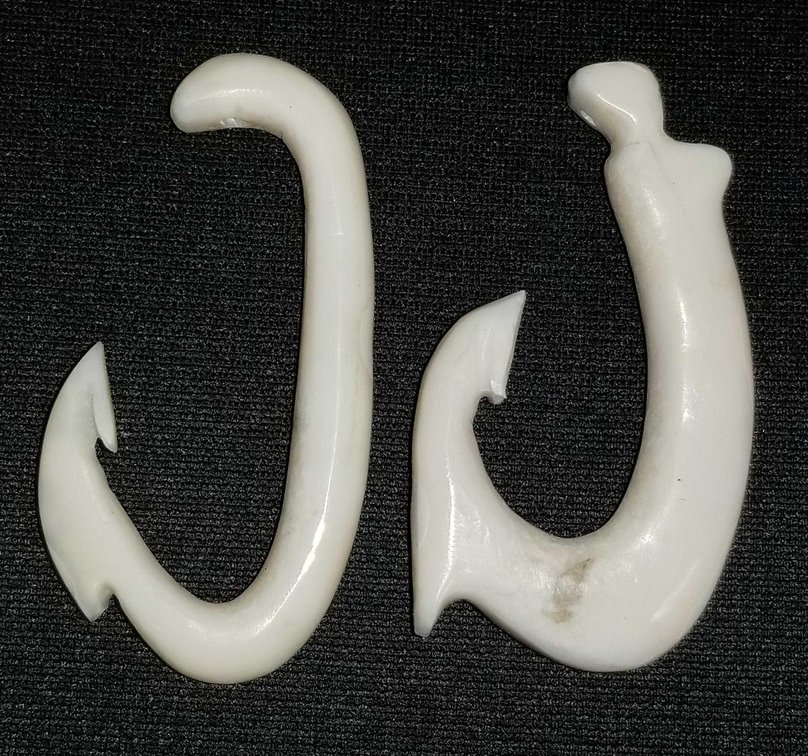 Two carved ivory fish hooks 