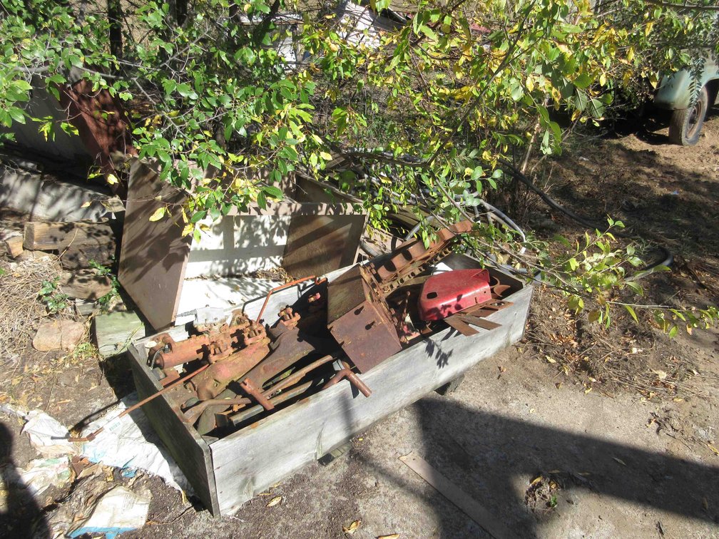 Scrap pile in crate and along outside wall of shed